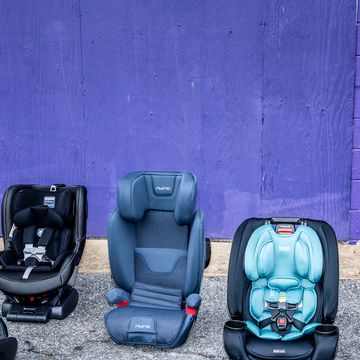 four car seats on the ground next to a car