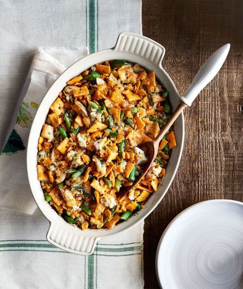 green bean barley chicken casserole in a white oval baking dish with a wooden spoon