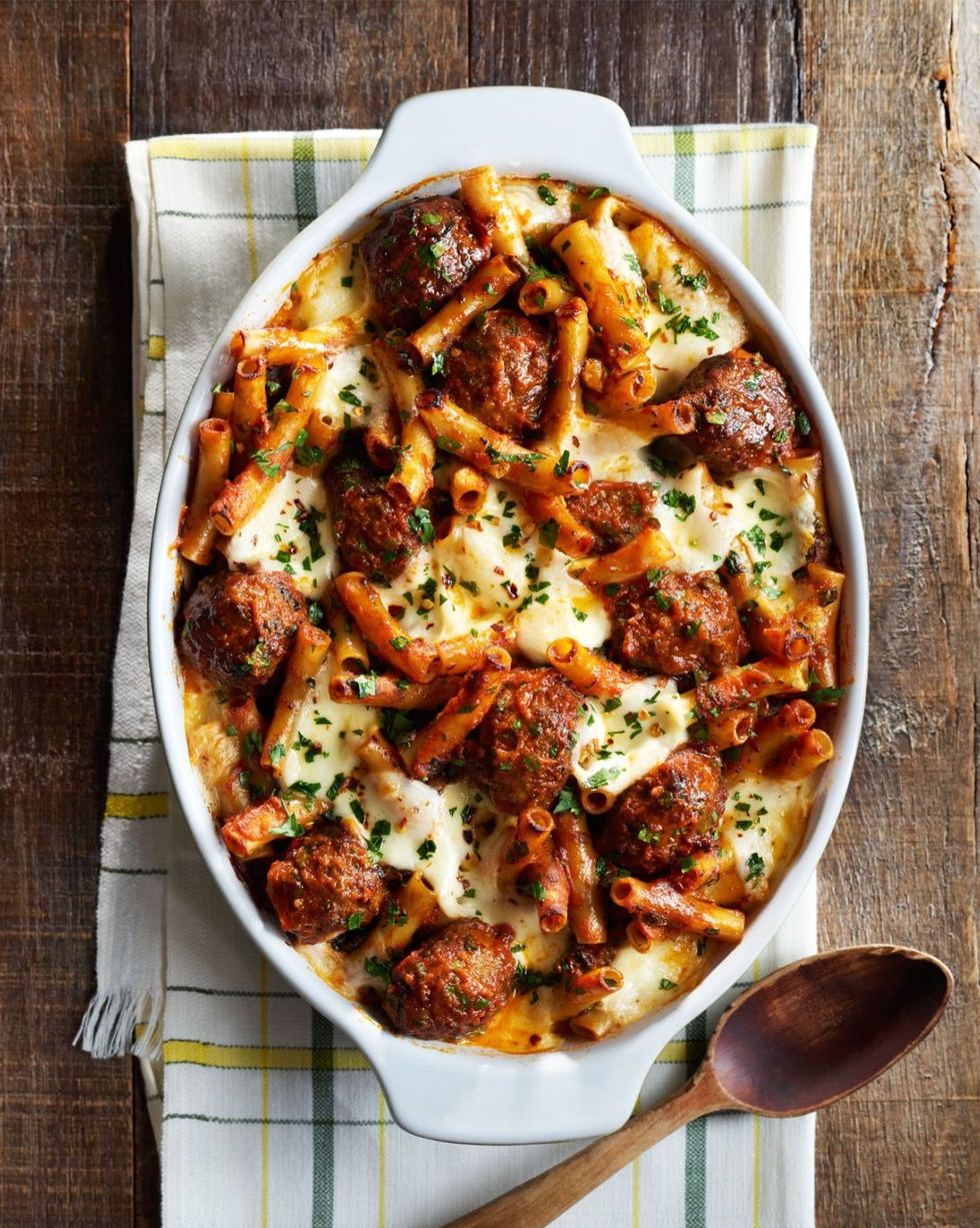 meatball spinach baked ziti in a white oval casserole dish