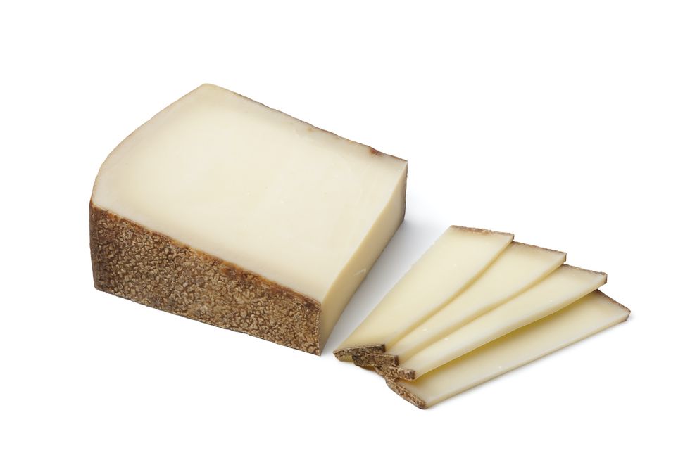piece of swiss gruyere cheese ans slices on white background