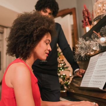 christmas songs   young woman playing piano during holidays