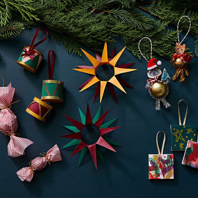 assortment of homemade christmas ornaments set against a dark background and pines