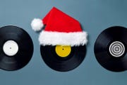 three black vinyl labels with a red plush santa claus hat on a blue background