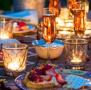 outdoor patio table set with citronella candles surrounded by dessert wine and strawberry tarts