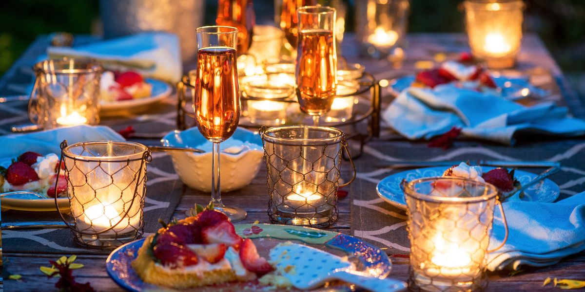 outdoor patio table set with citronella candles surrounded by dessert wine and strawberry tarts