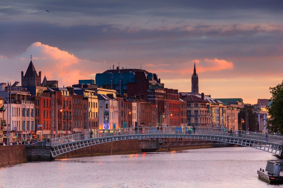 people walking on the half penny bridge at sunset, dublin ireland