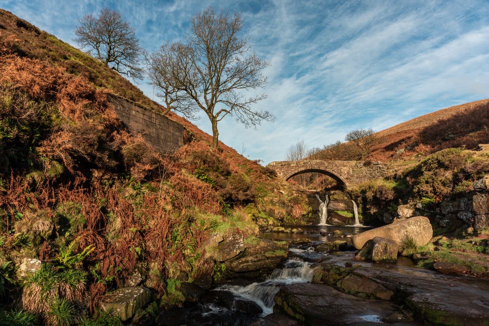 a waterfall and packhorse stone bridge at three shires head in the peak district national park