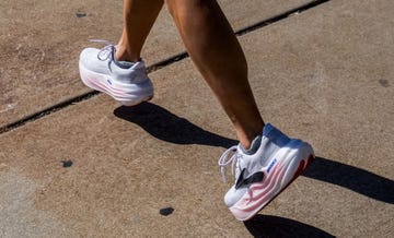 bottom half of someone's legs running down a pavement in white and pink shoes