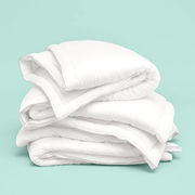 folded stack of good housekeeping best comforters on a blue background