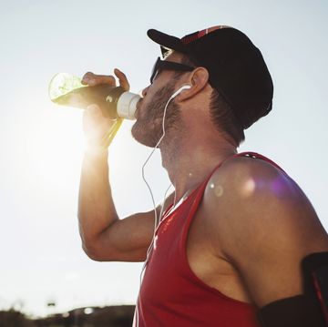 sport guy on a running training outdoors drinking water