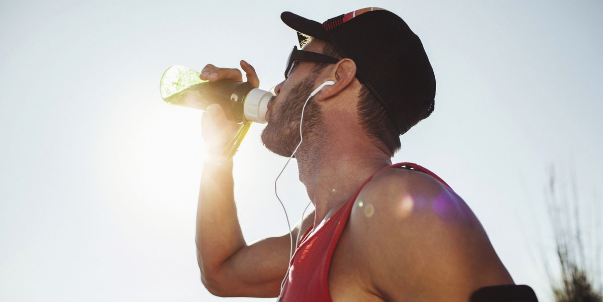 sport guy on a running training outdoors drinking water