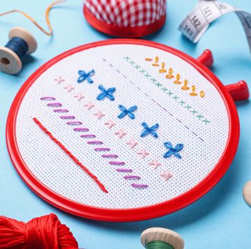 embroidery and different sewing accessories on light blue background