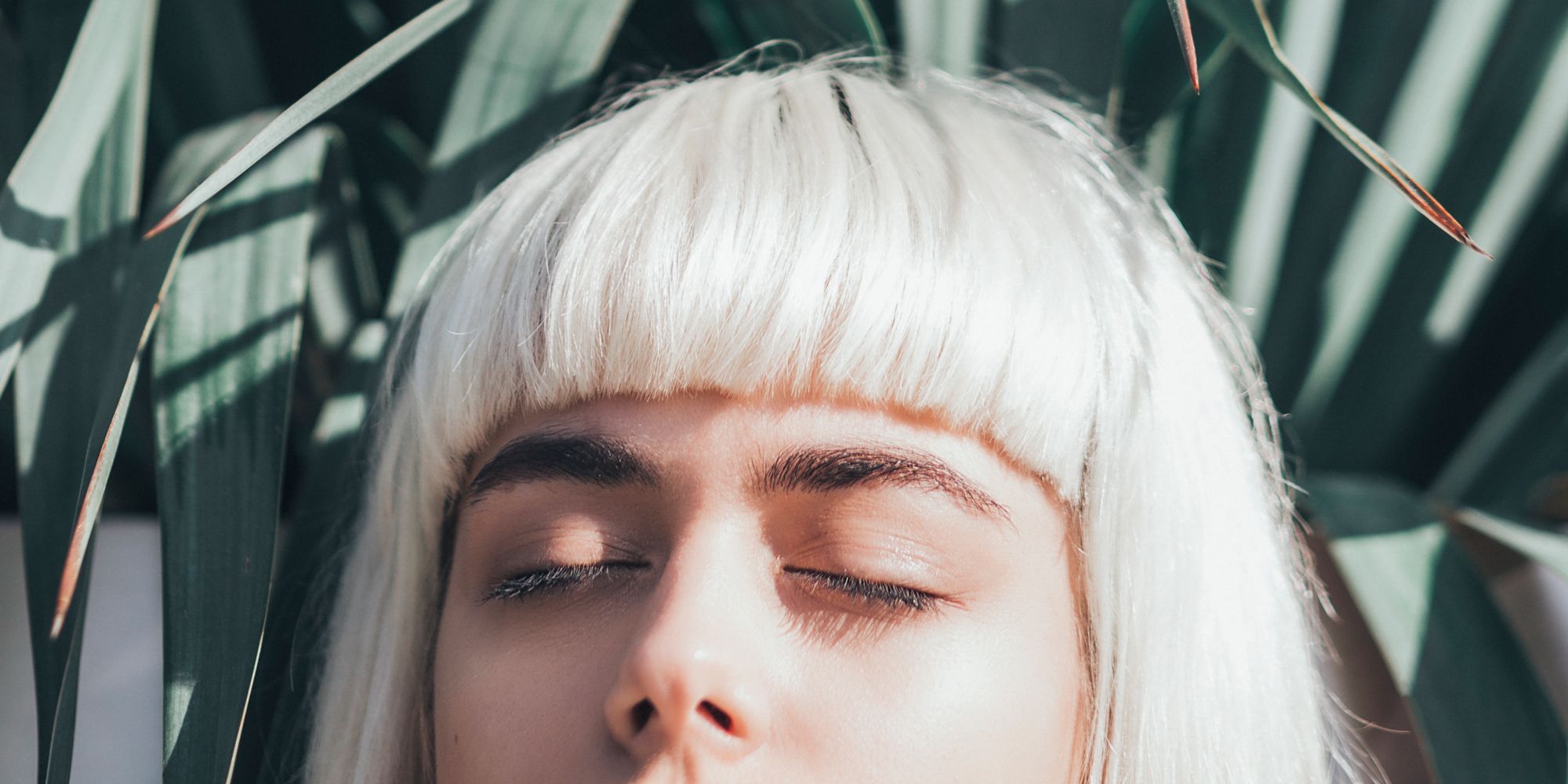 woman with bleached blonde hair and dark eyebrows with eyes closed