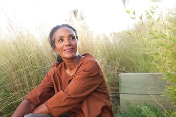 woman smiling, surrounded by grasses and nature outdoors