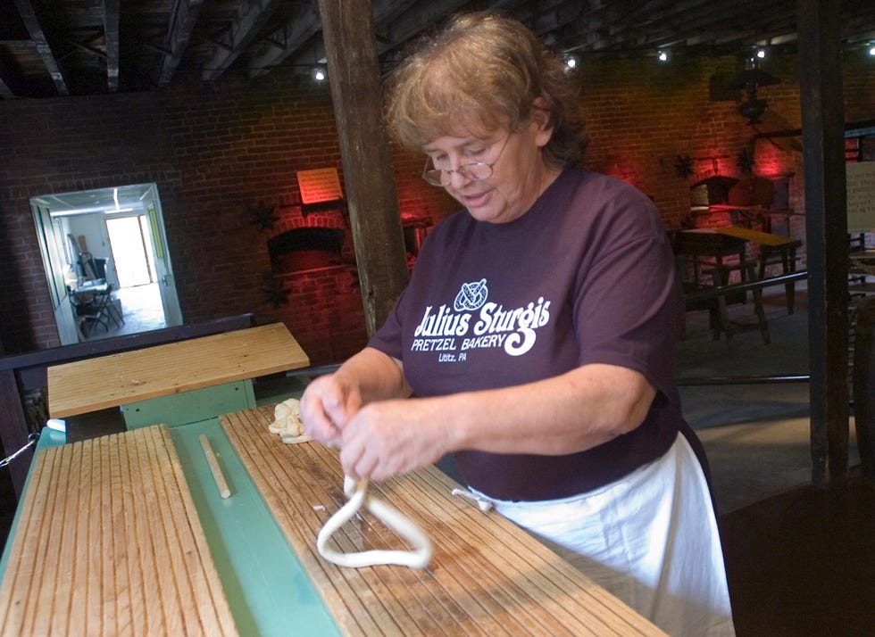 carol a thompson, a tour guide at the julius sturgis bakery, demonstrates how to twist a pretzel during a tour the julius sturgis pretzel bakery tours are a good housekeeping pick for best factory tours