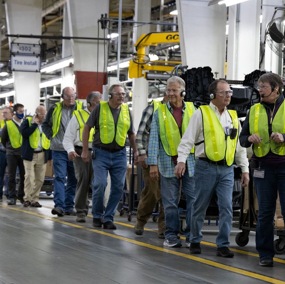 a crowd of people wearing neon work vests at the polaris factory tour, a good housekeeping pick for best factory tours