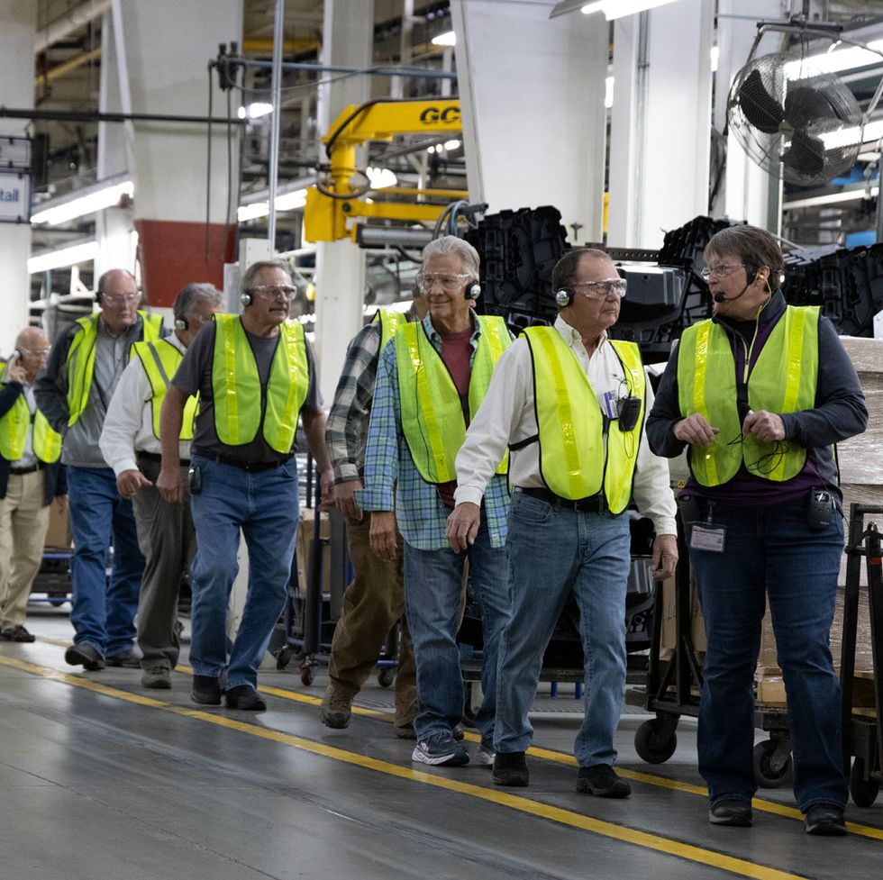 a crowd of people wearing neon work vests at the polaris factory tour, a good housekeeping pick for best factory tours