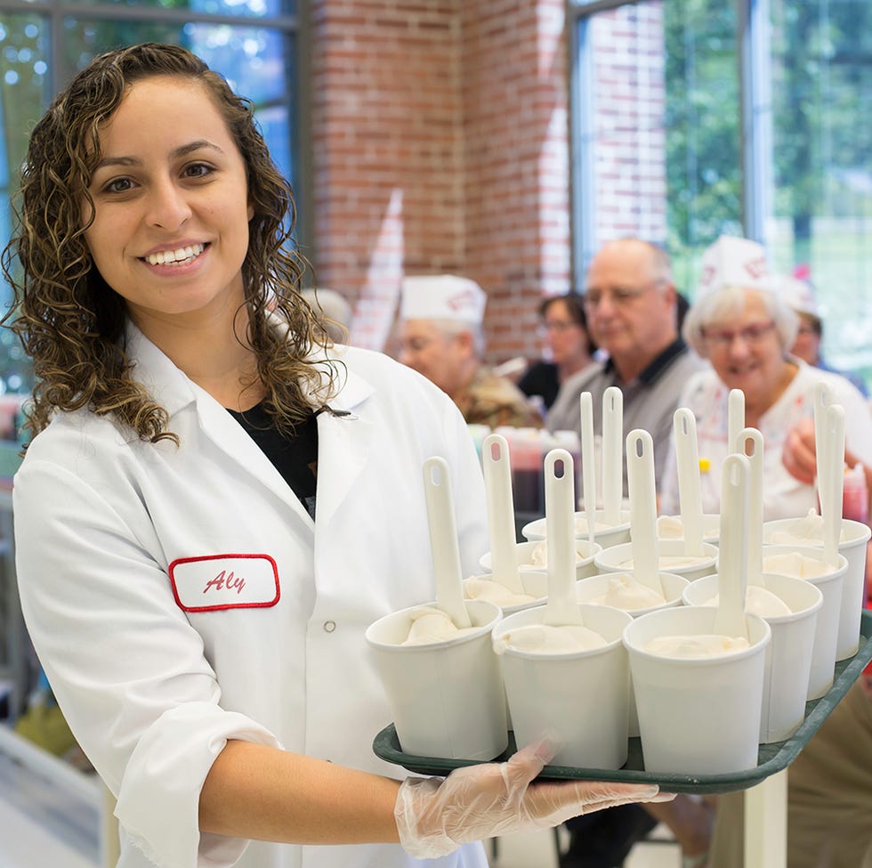 worker in a lab coat holds up a tray of different ice creams from turkey hill, a good housekeeping pick for best factory tours