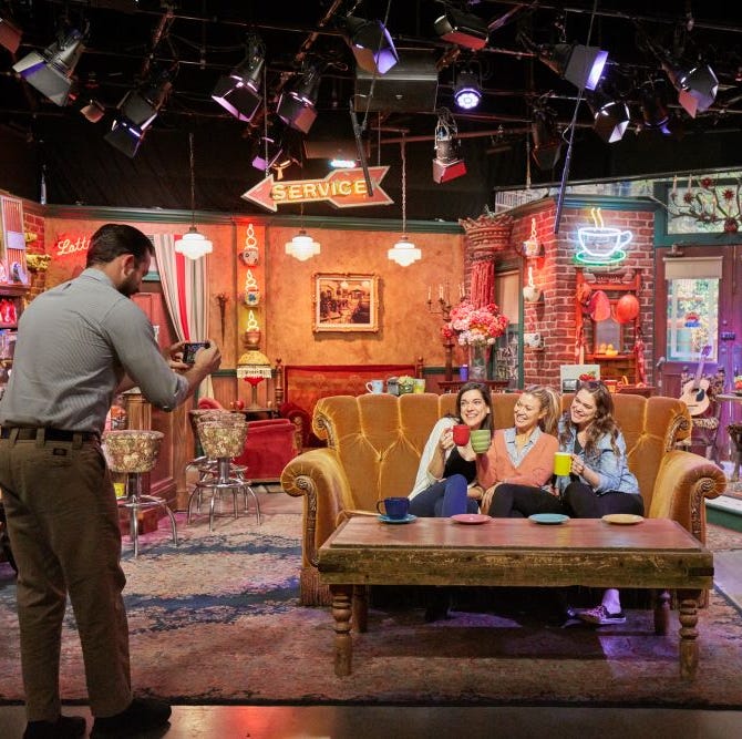 three visitors posing on the central perk couch as part of the warner bros studio tour, a good housekeeping pick for best factory tours