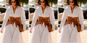 a woman at fashion week wears a white long sleeve flowy dress cinched with a belt in a roundup of the best flowy dresses for women 2022