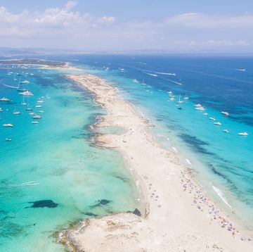 aerial overhead view of large amount of yachts anchored off the coast of formentera ibiza, with turquoise mediterranean sea and ocean blue water