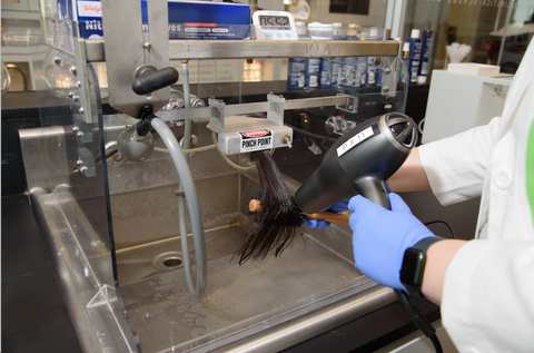 the good housekeeping institute beauty lab tests a hair dryer on a hair sample in lab