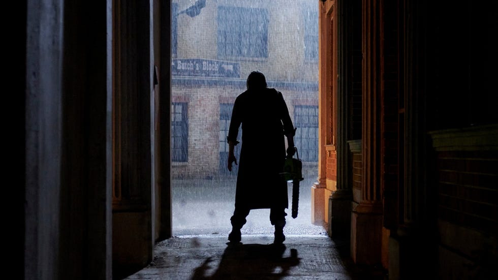 leatherface stands in the doorway with a chainsaw in a scene from texas chainsaw massacre, a good housekeeping pick for best halloween movies on netflix