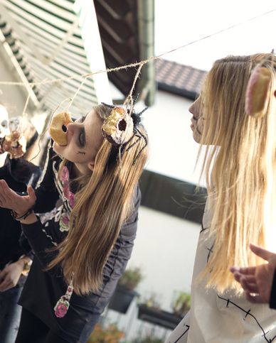 halloween party guests in spooky makeup try to eat donuts suspended from string without using hands as a game