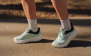 close up of the bottom half of someone's legs wearing a pair of green and black hoka running shoes and quarter length socks
