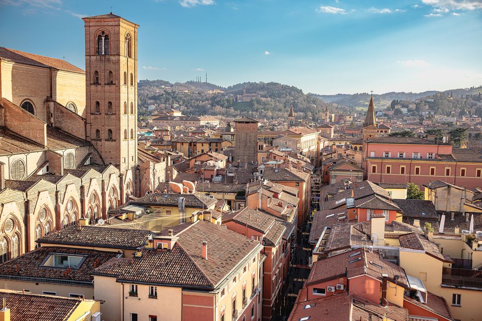 residential houses and buildings surrounding basilica di san petronio with bell tower in bologna, italy on a beautiful sunny day at springtime