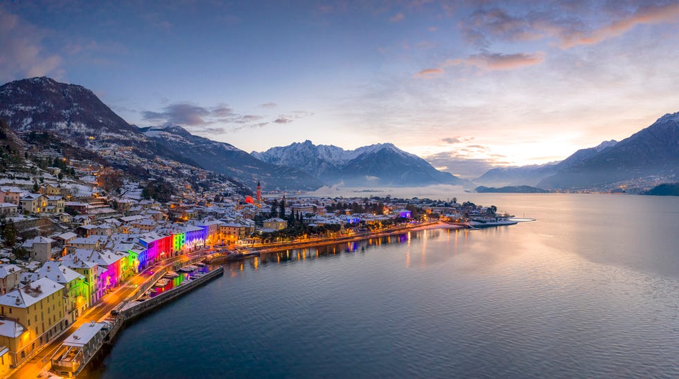 snowy buildings of domaso old town embellished by christmas lights at dawn, aerial view, lake como, lombardy, italy