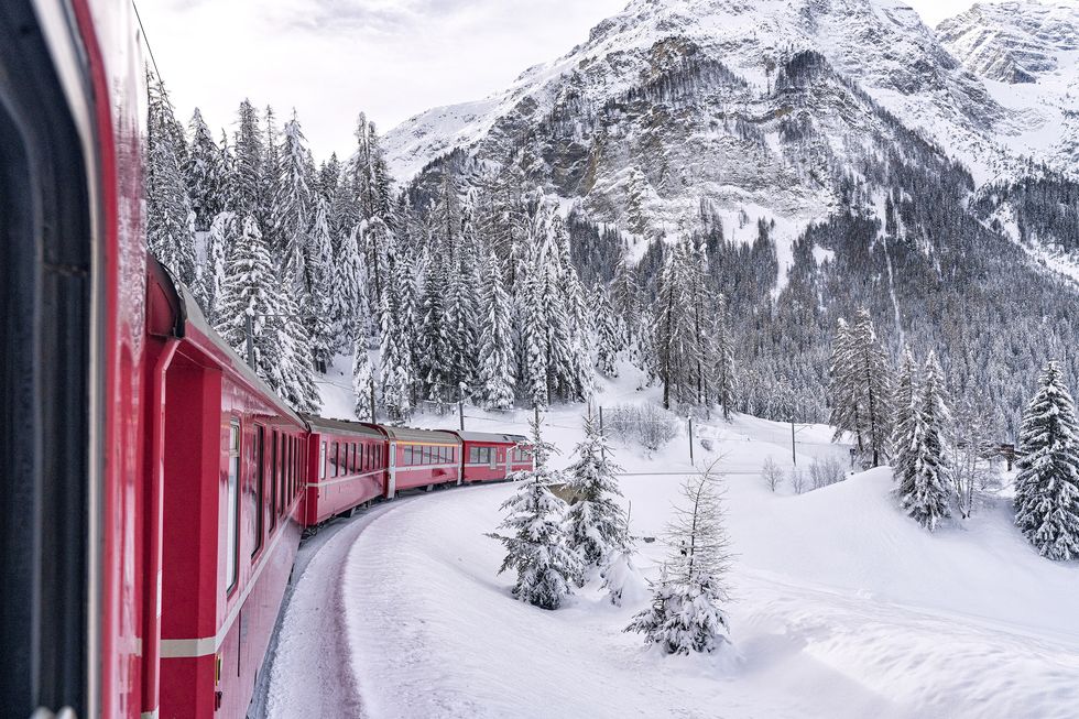 bernina express train in the winter forest covered with snow, preda bergun, albula valley, canton of graubunden, switzerland