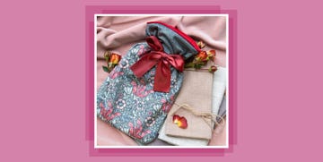 a patterned hot water bottle with a ribbon on a sheet with roses
