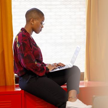 side view of woman working on laptop near window