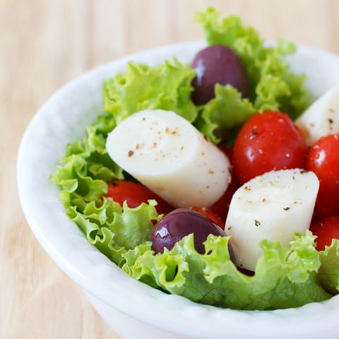 fresh salad of heart of palm palmito, cherry tomatos and olives on white plate selective focus copy space