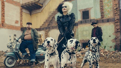 cruella walks a trio of dalmatians in a scene from 'cruella,' a good housekeeping pick for best halloween movies for kids