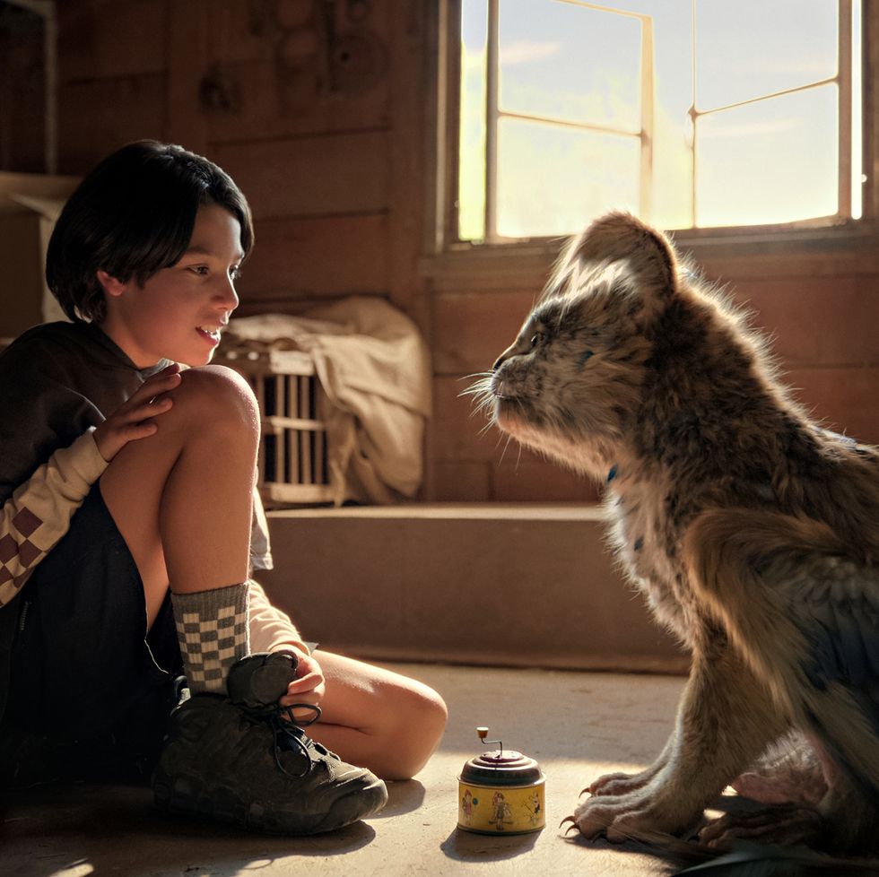 a kid sits calmly next to a furry creature in a scene from chupa, a good housekeeping pick for best kids' movies 2023