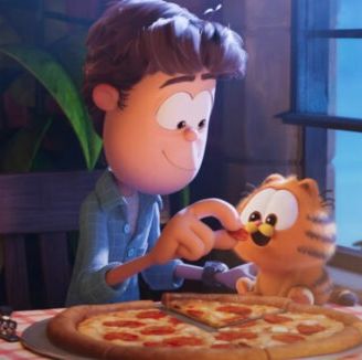 jon feeds a baby garfield some pizza in a scene from the garfield movie