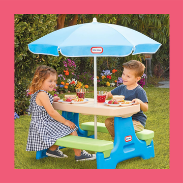 a group of kids sitting around a table with umbrellas