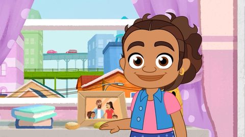 the 6 year old alma stands in front of a family photo in a scene from alma's way the show is a good housekeeping pick for best kids tv shows