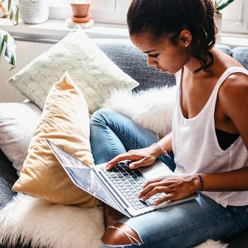 young person sitting on their couch while using their laptop
