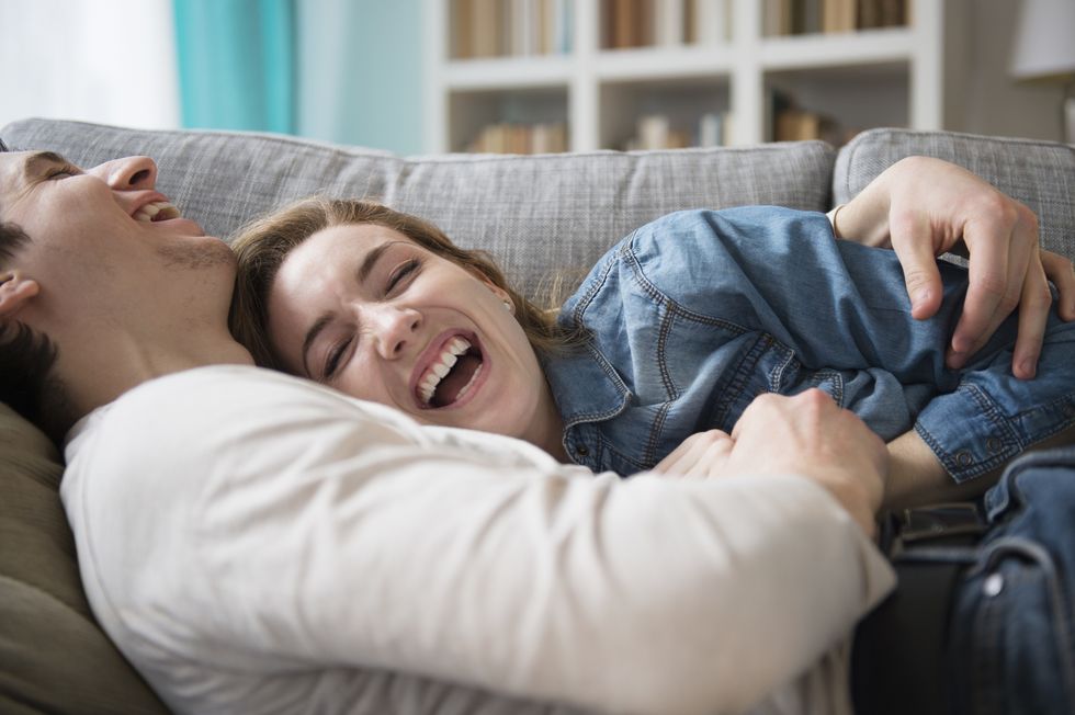 couple lying on a couch together laughing and cuddling