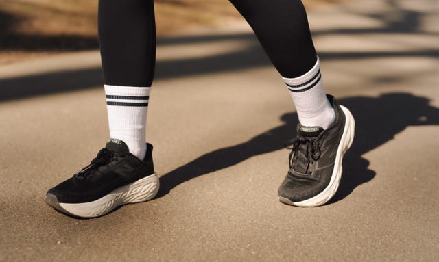 a pair of legs wearing black leggings, white socks and black and white cushioned running shoes
