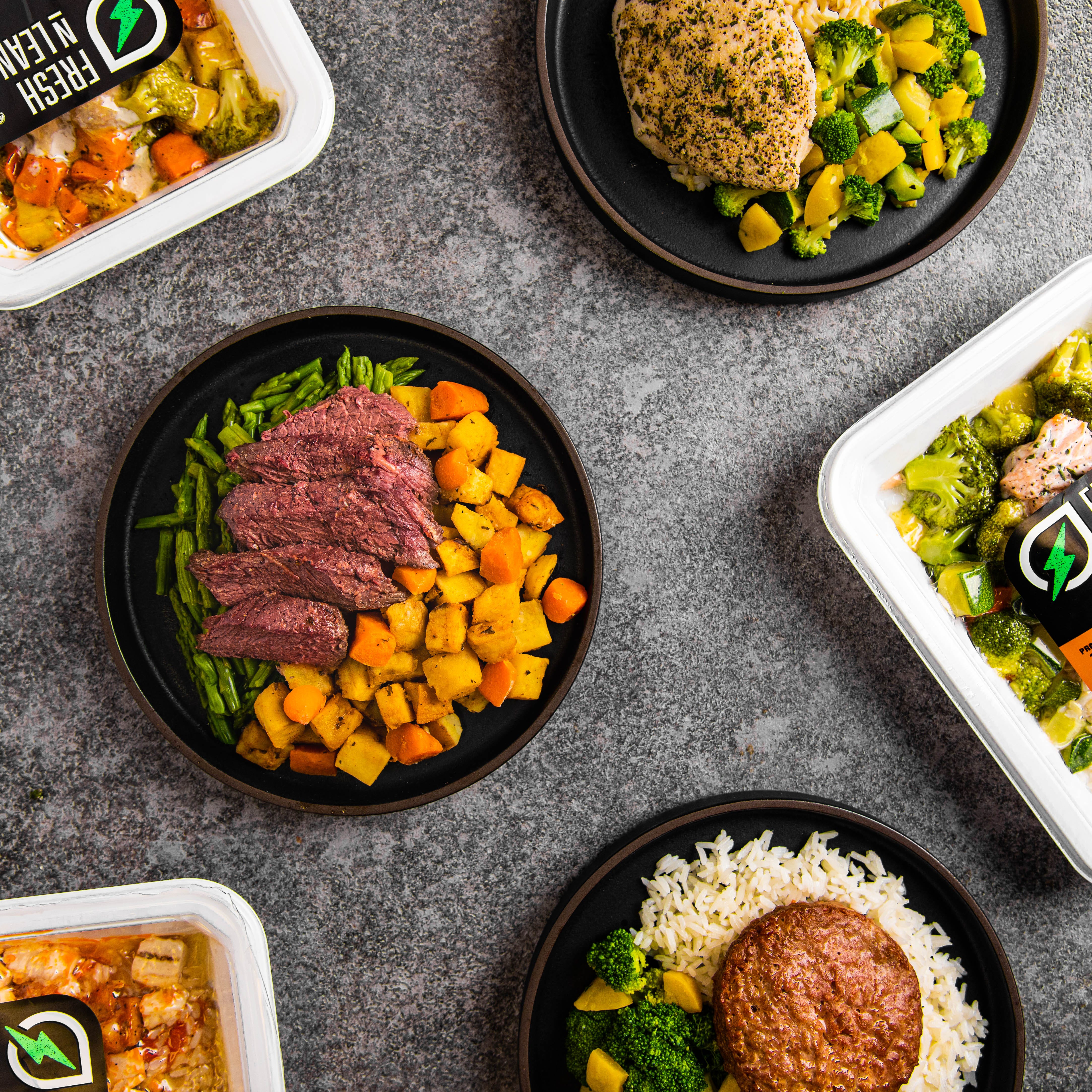 steak with sweet potatoes and asparagus and chicken with broccoli on a marble countertop from fresh n lean, a good housekeeping pick for best healthy meal delivery service