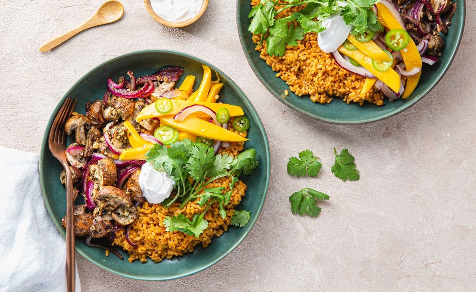 a vegan meal of rice, mushrooms and mango in a teal bowl on a slate countertop from purple carrot, a good housekeeping pick for best healthy meal delivery service