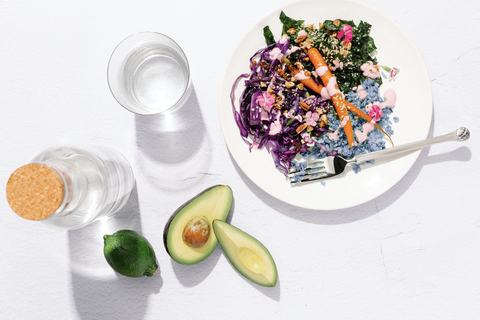 a colorful meal of cabbage, carrots, kale, cauliflower rice and avocado on a white background from sakara life, a good housekeeping pick for best healthy meal delivery service