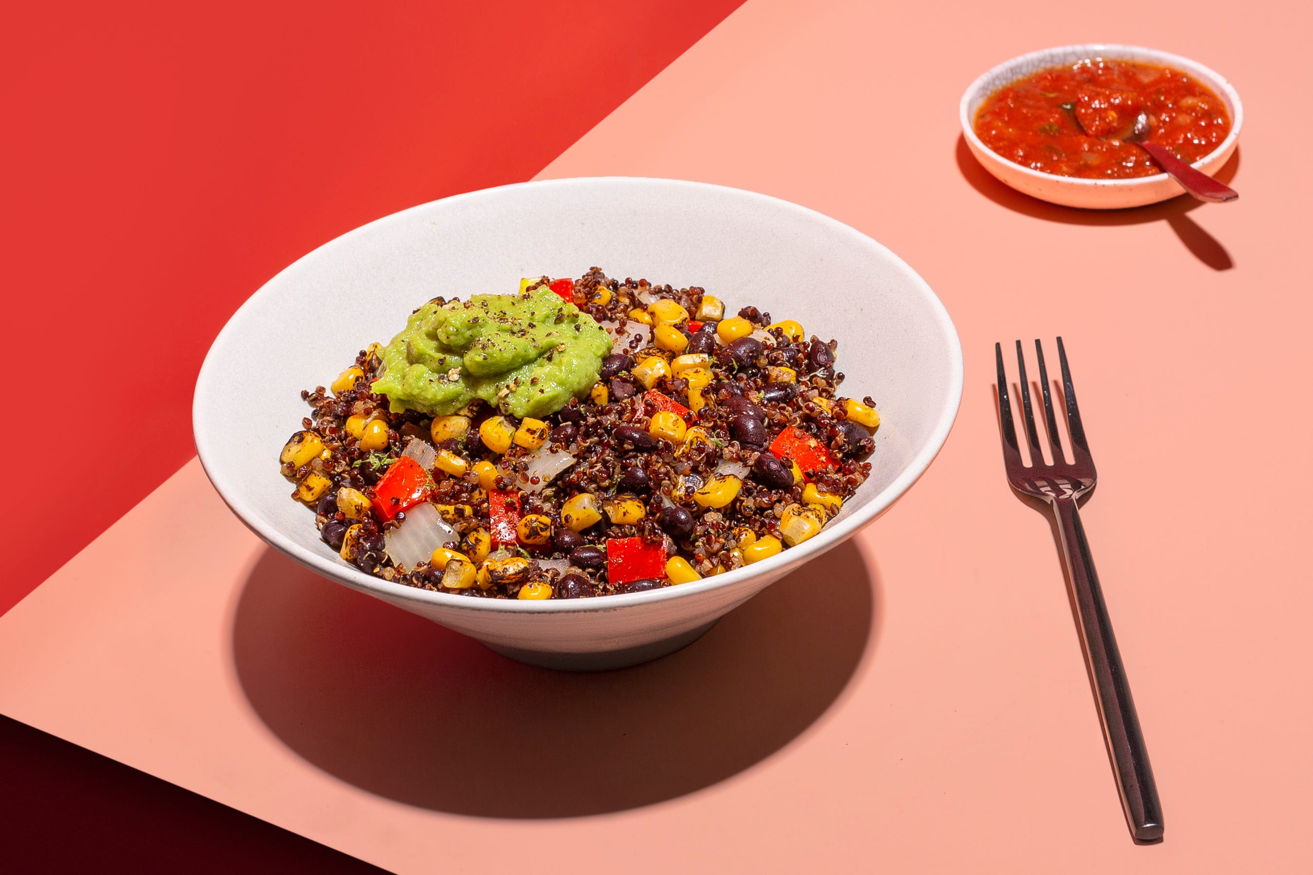 a grain bowl with guacamole on a red and pink background from sunbasket, a good housekeeping pick for best healthy meal delivery service