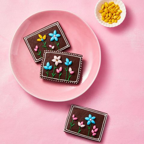 chocolate sugar cookies with flowers piped on top, on a pink plate