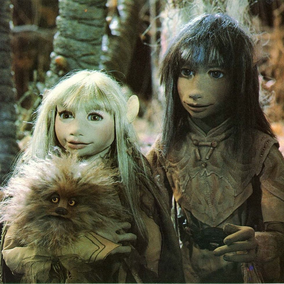 two gelflings hold an animal in a scene from the dark crystal
