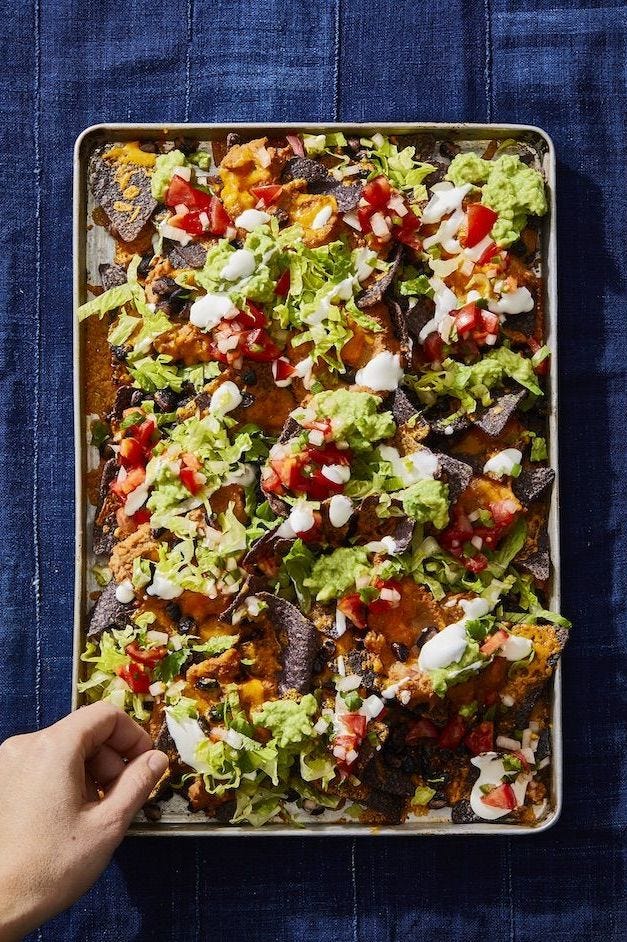 nachos with beans, guac, cheese, sour cream on a sheet pan